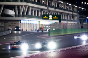 A Cadillac V-Seriues.R and an Aston Martin Valkyrie approaching turn 1, past the pit lane exit, at Qatar's Losail International Circuit.
