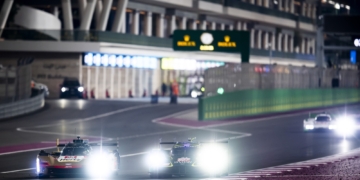 A Cadillac V-Seriues.R and an Aston Martin Valkyrie approaching turn 1, past the pit lane exit, at Qatar's Losail International Circuit.