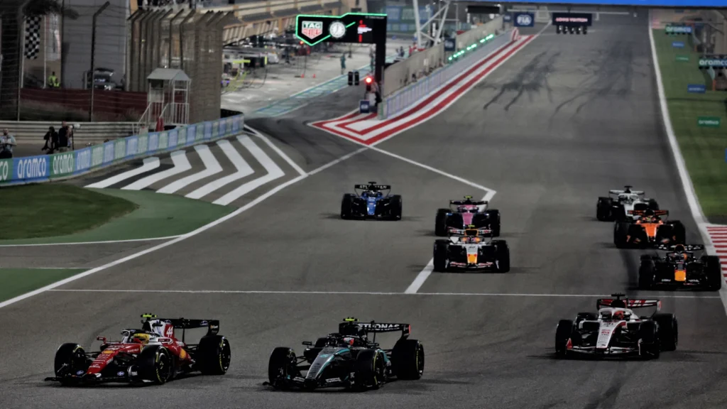 A selection of F1 cars performing a practice start in 2026 Bahrain testing, led by Ferrari's Lewis Hamilton and Mercedes' Kimi Antonelli.